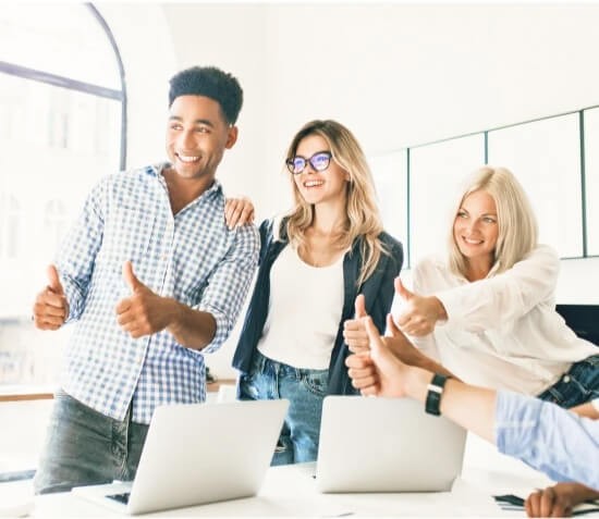 A group of coworkers standing together and giving a thumbs-up gesture.